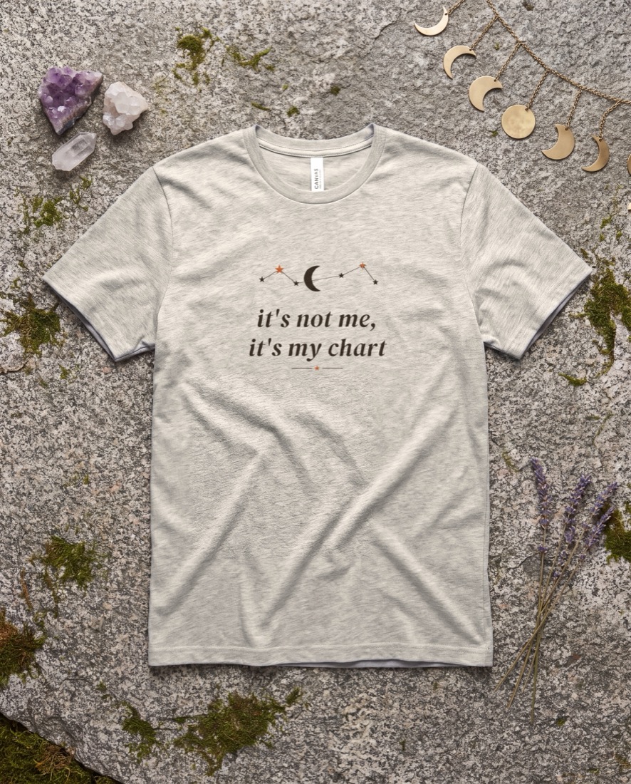 It's Not Me, It's My Chart tee, flat lay on a styled celestial surface