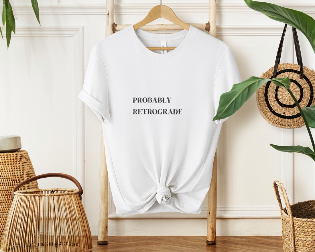 White Probably Retrograde tee hanging in a styled boho scene